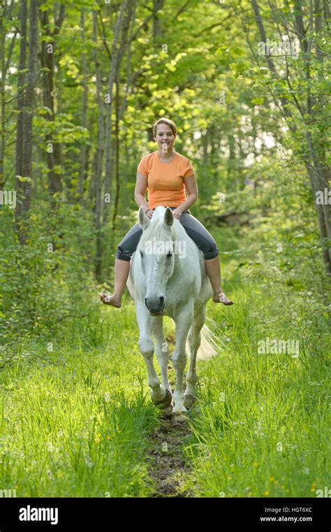 Junge Frau Reiten Ohne Sattel Und Bridleless Auf Rückseite Ein Graues Pferd Im Wald Stockfoto
