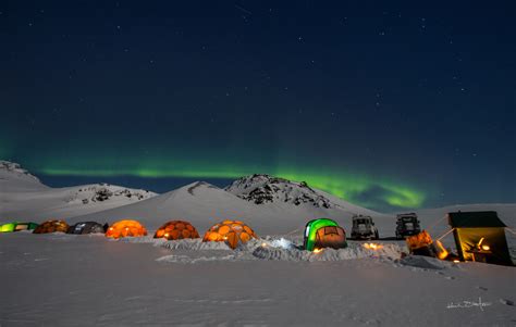 Tents In The Snow With An Aurora Light Above Them And Some Mountains