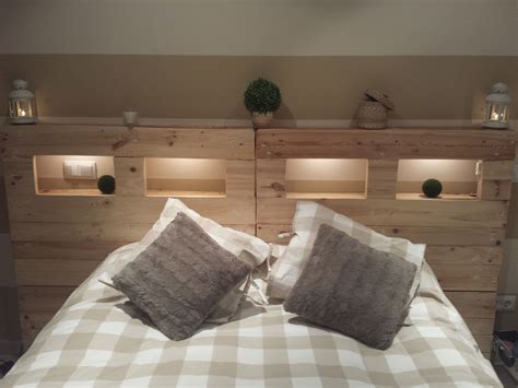 A Bed With Two Pillows On It And Some Lights Above The Headboard In
