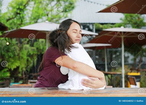 asian mother embracing her daughter with love on the wood table at outdoor restaurant stock