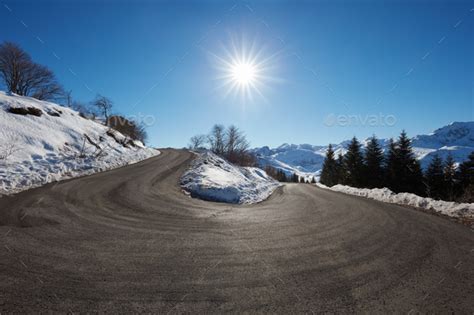 Large Empty Mountain Road Curve On Alps With Snow On Sides Blue Stock