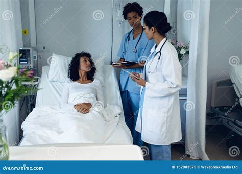 Female Doctors Interacting With Female Patient In The Ward Stock Image