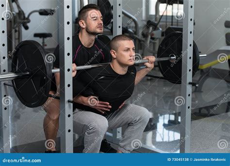 Gym Coach Helping Man On Barbell Squat Stock Photo Image Of