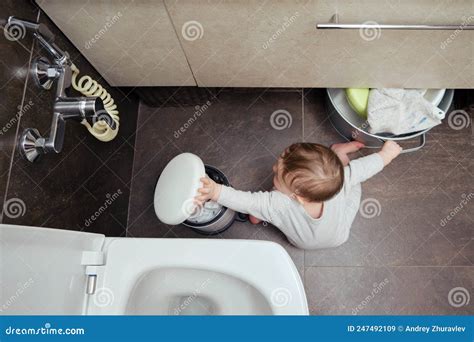 Niño Pequeño Está Jugando En El Baño Con Una Papelera Niño Juega En El Suelo Marrón En Un Baño