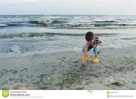 The Little Boy By The Sea Throws Stones In Water Sunset Stock Photo
