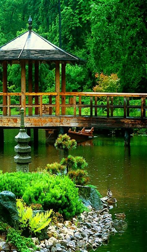 A Gazebo In The Middle Of A Pond With Rocks And Plants Around It