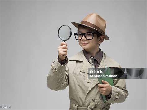 Little Detective Looking Through Magnifying Glass On Gray Background