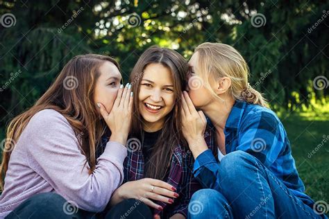 Three Young Attractive Woman Sharing Secrets Sitting On Green Grass In The Park Cheerful