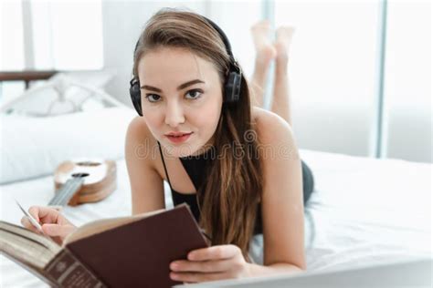 Portrait Of Attractive Woman Is Relaxing On Bedroom While Listen Music