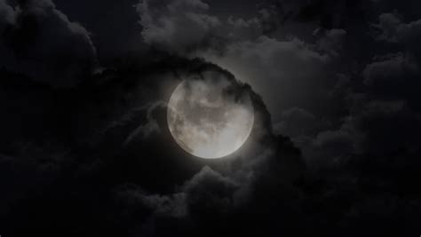 Dark Night Sky With A Full Moon Shining Bright As Clouds Move Across