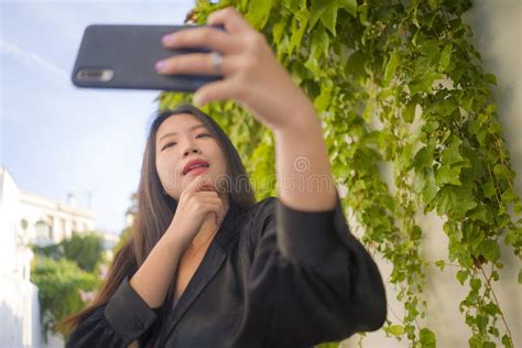 Young Happy And Beautiful Asian Chinese Woman Enjoying Outdoors Taking Selfie With Mobile Phone