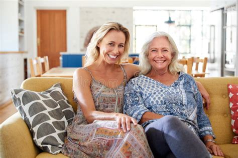 Portrait Of Smiling Mother With Adult Daughter Relaxing On Sofa At Home Stock Image Image Of