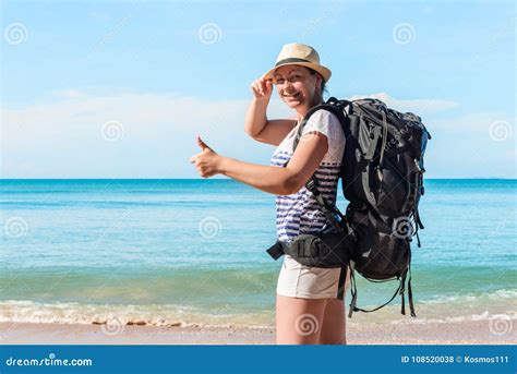 Young Female Tourist With A Backpack Happy On The Beach Stock Photo