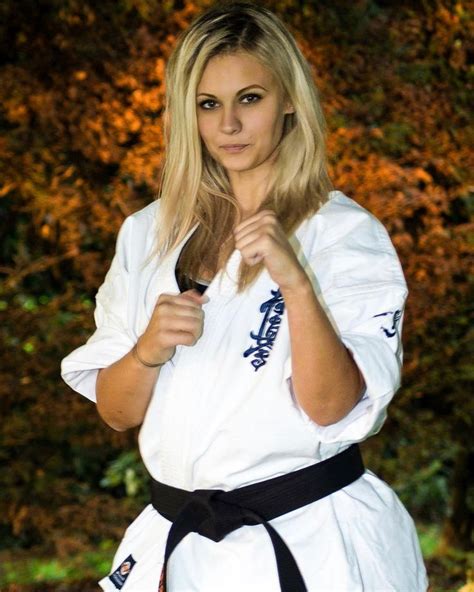 A Woman In A Karate Outfit Posing For The Camera With Her Black Belt Around Her Waist
