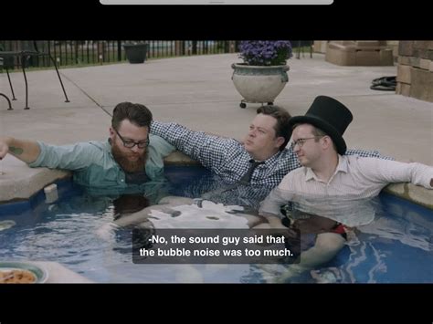 three men are sitting in the pool and one is pointing at something
