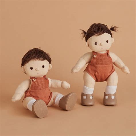 two small dolls sitting next to each other on a brown background one is wearing an orange shirt