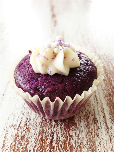 A Purple Cupcake With White Frosting And Sprinkles On The Top