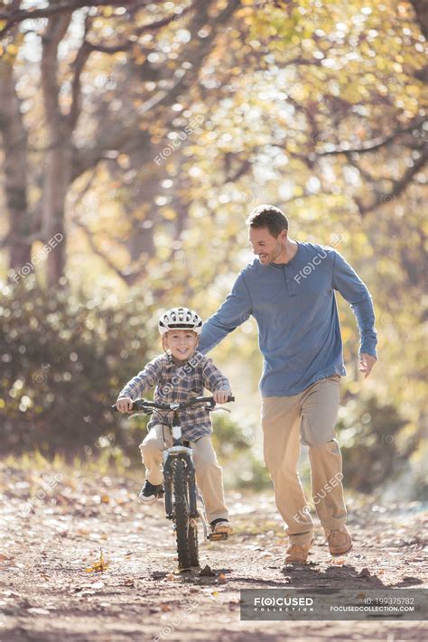 Father Teaching Son To Ride A Bicycle On Path In Woods — Learning