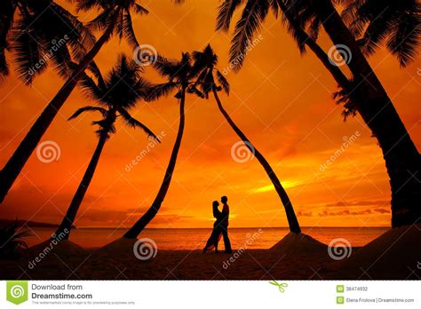 Two People Kissing On The Beach With Palm Trees In The Background And