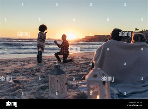 man proposing woman her loved at sea shore marriage proposal at sunset beach with friends