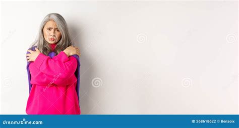 Defensive And Offended Asian Middle Aged Woman Hugging Body Comforting Herself And Looking