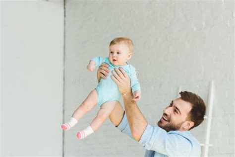 Smiling Father Raising Infant Daughter Stock Photo Image Of Indoors