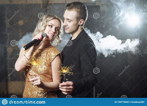 Portrait Of Happy Young Couple With Sparklers Singing With Microphone