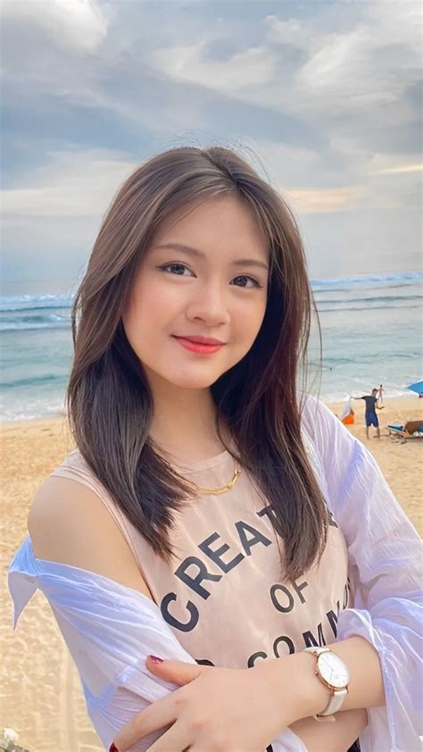 A Woman Standing On Top Of A Sandy Beach Next To The Ocean With Her Arms Crossed