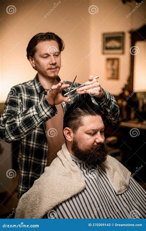 view on bearded man at barbershop and barber cuts and styles his hair stock image image of