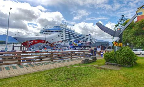 A Large Cruise Ship Docked In The Water Next To A Grassy Area With