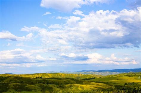 Hills With Green Grass And Blue Sky With White Puffy Clouds Stock Photo