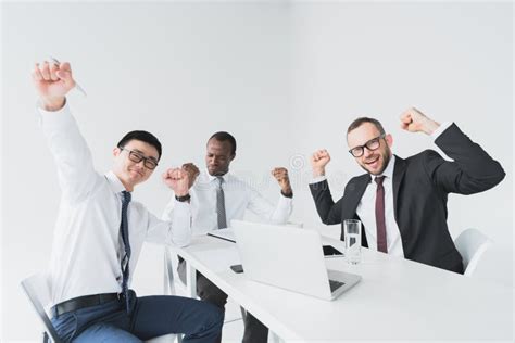 Multicultural Excited Businessmen Looking At Camera While Sitting At