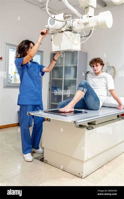 Full Body Of Female Nurse In Blue Uniform Adjusts X Ray Machine For