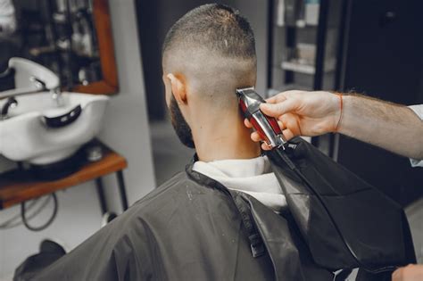 Um homem corta o cabelo em uma barbearia Foto Grátis