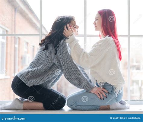 Two Women Dressed In Sweaters Sit By The Window And Gently Hug Lesbian