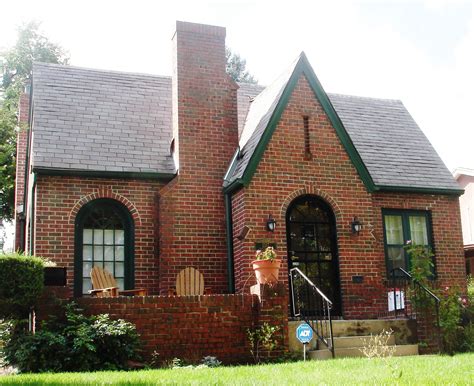 A Red Brick House With Green Trim On The Front Door And Windows Is