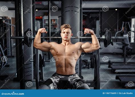 Close Up Of A Muscular Young Man Lifting Weights In Gym On Dark