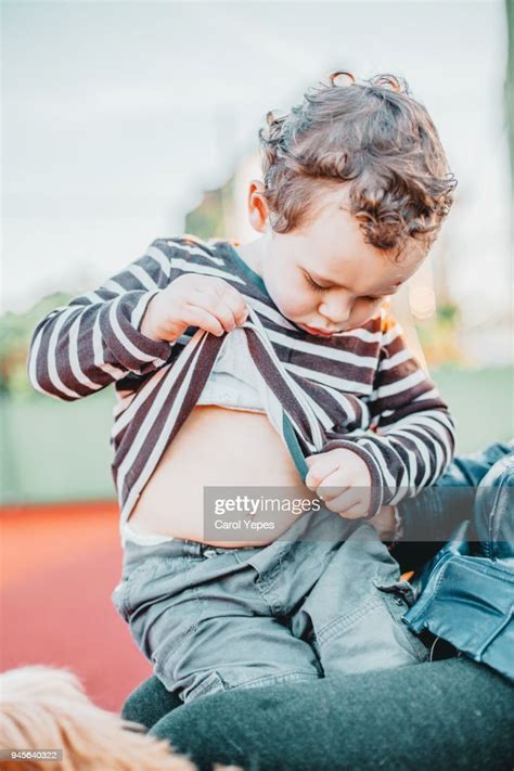Little Boy Looking At His Belly Button Outdoors Photo Getty Images