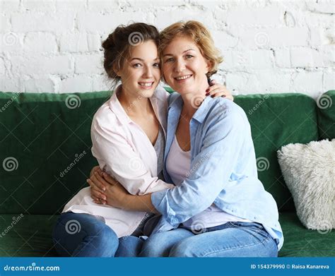 Adult Daughter Hugs Mom And Both Are Smiling At The Camera Stock Photo