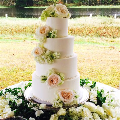 four tiered smooth buttercream wedding cake with fresh cascading flowers by les amis bake shoppe