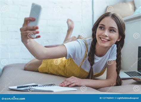 Smiling Girl Taking Selfie On Smartphone While Lying On Sofa With Copybook Stock Image Image