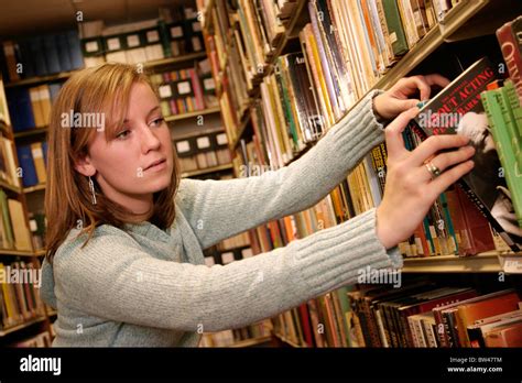 Young Woman In A Library Looking For Books Young Woman Student Looking