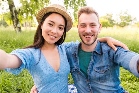 Free Photo Happy Multiracial Adult Couple Taking Selfie At Park