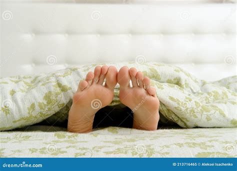 Bare Female Feet Sticking Out From Under The Blanket Stock Image