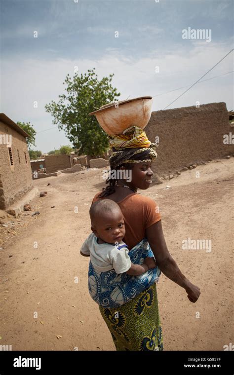 A Woman Carries A Child On Her Back In Niassan Village Burkina Faso