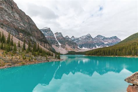 Turquoise Water Surround With Taiga Forest And Rocky Mountain In Summer
