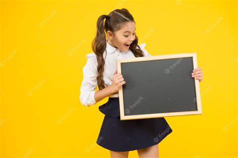 Co To Jest Zaskoczona Dziewczyna Trzyma Tablicę Na żółtym Tle Małe Dziecko Przygotowuje Tablicę
