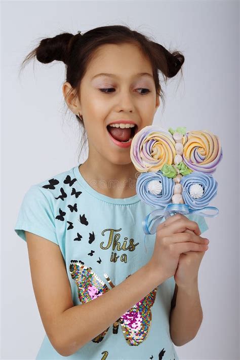 A Girl Holds In Two Hands Multicolored Candies On A Stick Showing Them