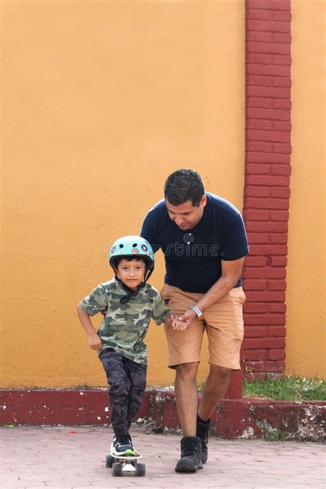 Latin Single Dad Teaches His Son To Ride A Skateboard With A Helmet