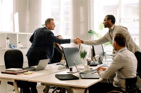 Businessmen Shaking Hands During Sales Meeting In Office Stock Photo